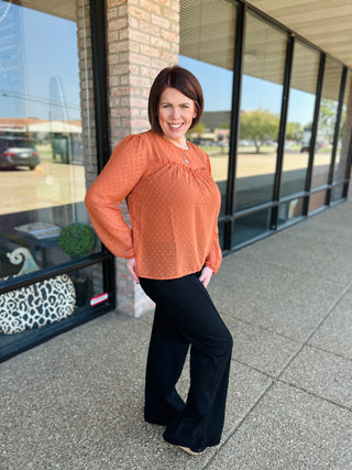 Woman wearing orange polka dot blouse with black pants, standing outside storefront