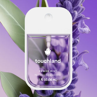 Touchland Power Mist hydrating hand sanitizer spray bottle displayed against lavender flowers background.