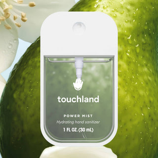 Touchland Power Mist hydrating hand sanitizer in clear bottle surrounded by fresh green fruit