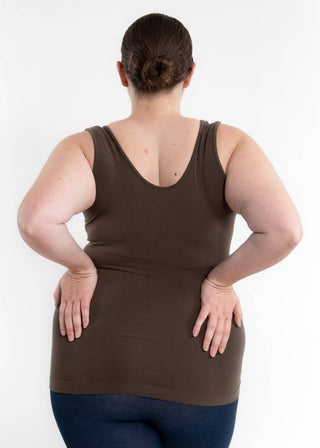 Woman wearing olive green reversible cami tank top, viewed from behind with hands on hips.