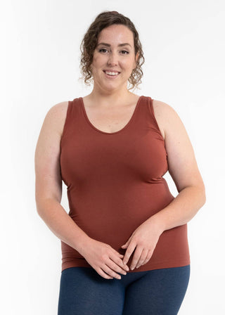 Woman wearing rust-colored sleeveless tank top with fitted silhouette against white background