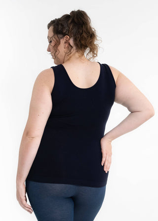 Woman wearing black reversible cami tank top with blue leggings, shown from behind against white background.