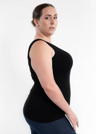 Woman wearing black sleeveless reversible cami tank top with fitted silhouette against white background