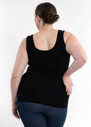 Woman wearing black reversible cami tank top with jeans, shown from behind against white background.