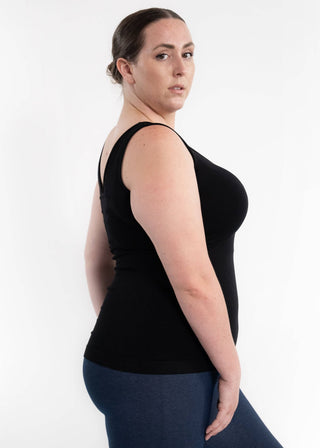 Woman wearing black reversible cami tank top with blue leggings, shown from side angle.