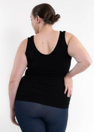 Woman wearing black reversible cami tank top and blue leggings, shown from behind.