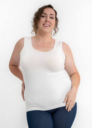 Woman wearing white reversible cami tank top with blue leggings against white background