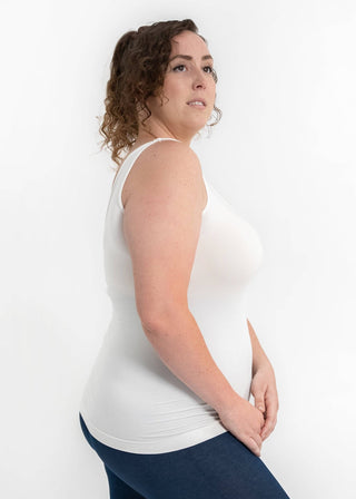 Woman wearing white reversible cami tank top with blue leggings, shown from side angle