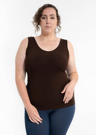 Woman wearing dark brown sleeveless tank top with blue jeans against white background