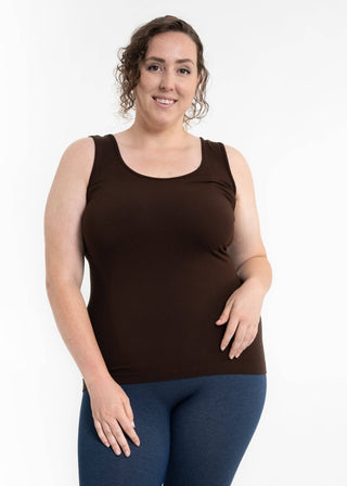 Woman wearing brown sleeveless tank top with blue jeans against white background