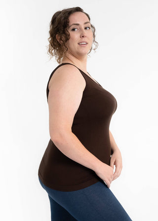 Woman wearing brown reversible cami tank top with blue leggings against white background