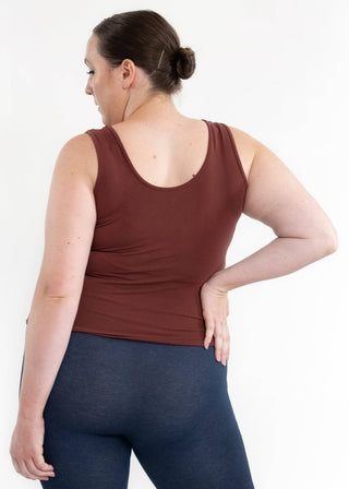 Woman wearing burgundy reversible cami tank top and navy leggings, shown from behind