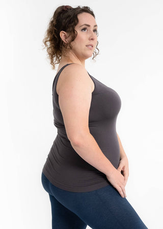 Woman wearing gray reversible cami tank top with blue leggings in side pose against white background.