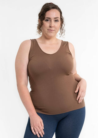Woman wearing brown sleeveless reversible cami top with blue jeans against white background