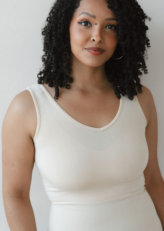 Woman wearing cream colored reversible cami tank top against neutral background