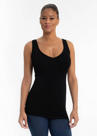 Woman wearing black fitted sleeveless camisole top with v-neck and blue jeans against white background.