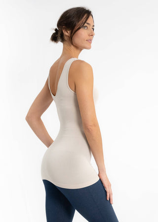 Woman wearing beige reversible cami top with navy leggings, shown from back view against white background.