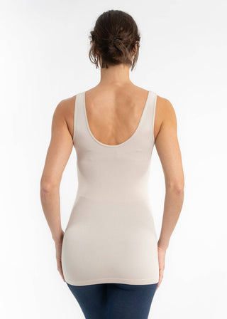 Back view of woman wearing beige sleeveless tank top with scoop neckline and dark jeans.
