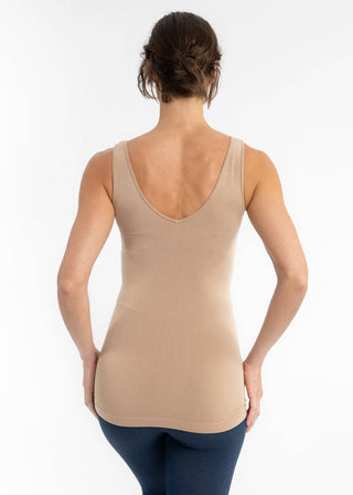 Woman wearing beige reversible cami top with v-neck back, paired with blue jeans, viewed from behind.