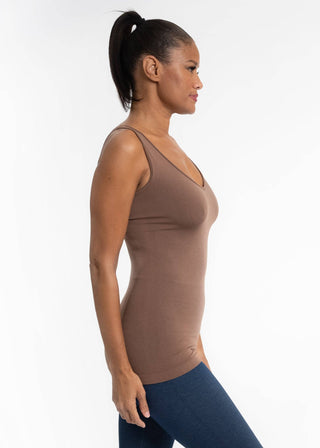 Woman wearing brown fitted sleeveless cami top with blue leggings in profile view