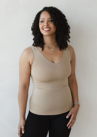 Woman wearing beige fitted reversible cami top with V-neckline, smiling against neutral background.