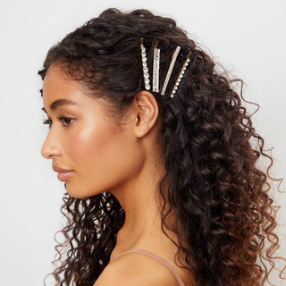 Woman with curly hair wearing decorative rhinestone bobby pins in a stylish hair accessory set.
