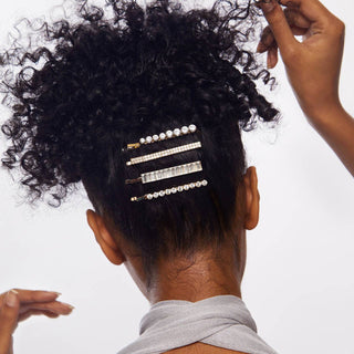 Person with curly hair wearing decorative rhinestone bobby pins in an updo hairstyle