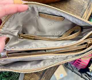 Open beige crossbody bag showing multiple zippered compartments with gray patterned interior lining and organization pockets.