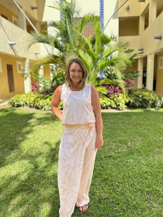 Woman wearing a tie-dye tank top and palazzo pants set standing in a tropical resort courtyard.
