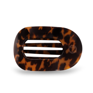Round tortoiseshell hair clip with oval cutout and decorative clasp mechanism on white background