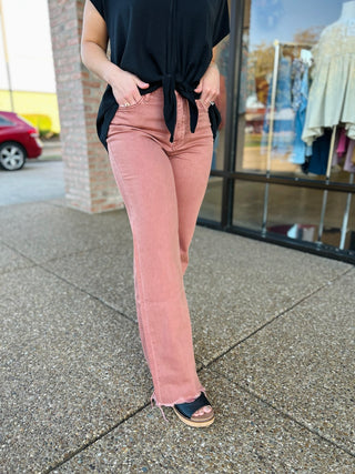 Woman wearing pink vintage flare jeans with raw hem and black top, standing on sidewalk
