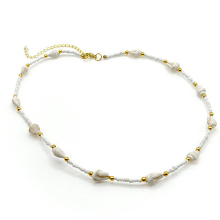White beaded necklace with gold accents and small shell details on white background