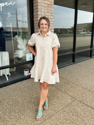Woman wearing a striped collared shirt dress with puff sleeves and ruffle hem, styled with wedge sandals.
