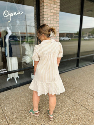Woman wearing a striped short-sleeve shirt dress with ruffled hem and puff sleeves, back view.