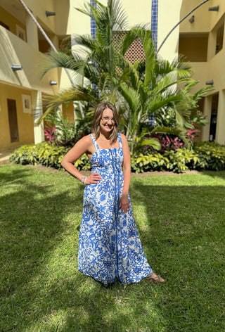 Woman wearing blue and white floral maxi dress standing on grass in tropical resort setting