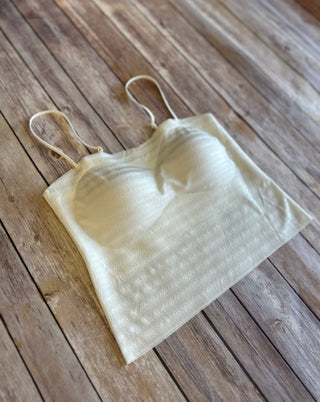 White shimmery striped bralette with thin straps lying flat on weathered wood surface