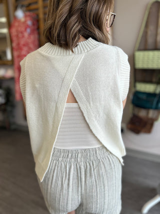 Woman wearing white knit sweater with open back detail and matching ribbed shorts from behind