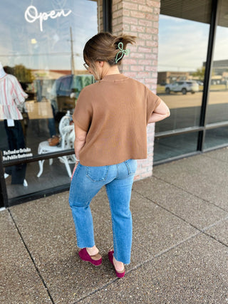 Woman wearing a cropped ribbed sweater top paired with straight-leg jeans, back view.