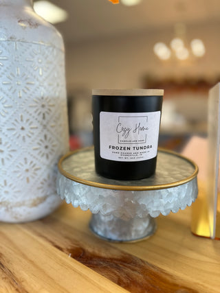 Black soy candle with wooden wick displayed on decorative metal stand next to white ceramic oil diffuser
