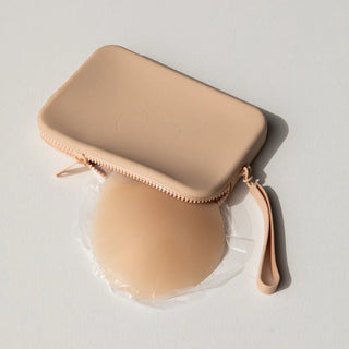 Clear silicone adhesive bra with nude zippered carrying case on white background