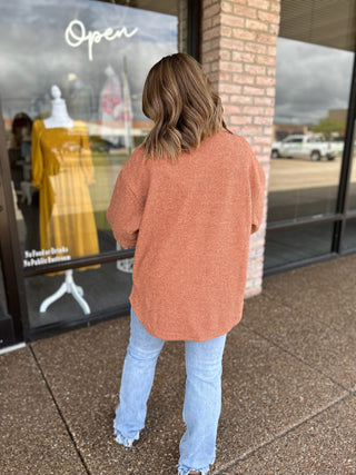 Woman wearing an oversized ribbed knit shacket paired with light wash distressed jeans, back view.