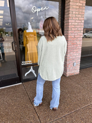 Woman wearing an oversized ribbed shacket with light wash jeans outside a boutique storefront.