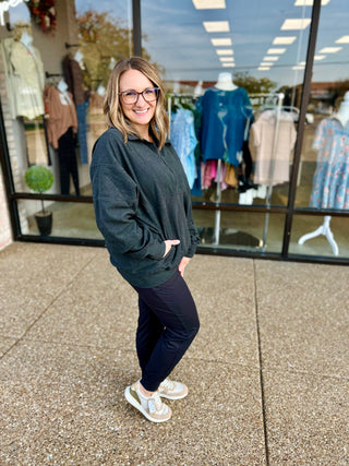 Woman wearing Slate Ridge Quarter Zip Pullover by Rae Mode, standing outside clothing store window display.