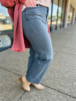 Woman wearing high-rise straight jeans in smoke grey with coral cardigan and nude flats on sidewalk.
