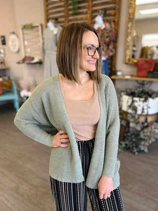 Woman wearing mocha ribbed square neck top with sage cardigan and patterned pants in retail store