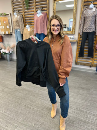 Woman holding black Jodifl Soft Summit Hoodie in clothing boutique store setting