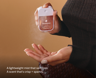 A hand spraying Touchland Power Mist hydrating hand sanitizer onto an open palm.