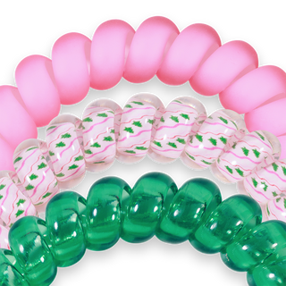 Three colorful spiral hair coils with pink, clear patterned, and green translucent designs on black background.
