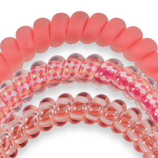 Three pink spiral hair coils with translucent and patterned designs on black background
