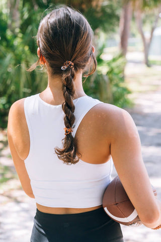 Woman with braided hair secured by TELETIES Spiral Hair Coils, holding a football outdoors.
